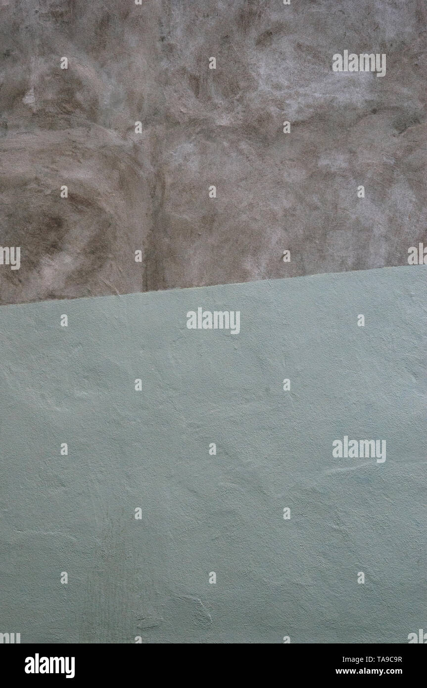 Un gros plan d'une partie de mur en plâtre brut et peint partiellement une pâle vert sauge Banque D'Images