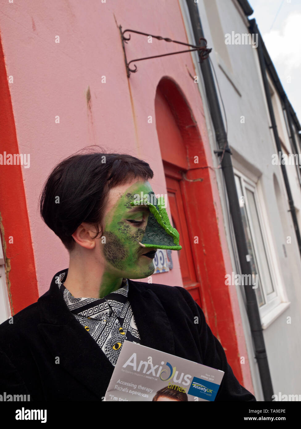 Une femme masquée est titulaire d'un magazine sur l'anxiété dans une rue de Brighton Banque D'Images