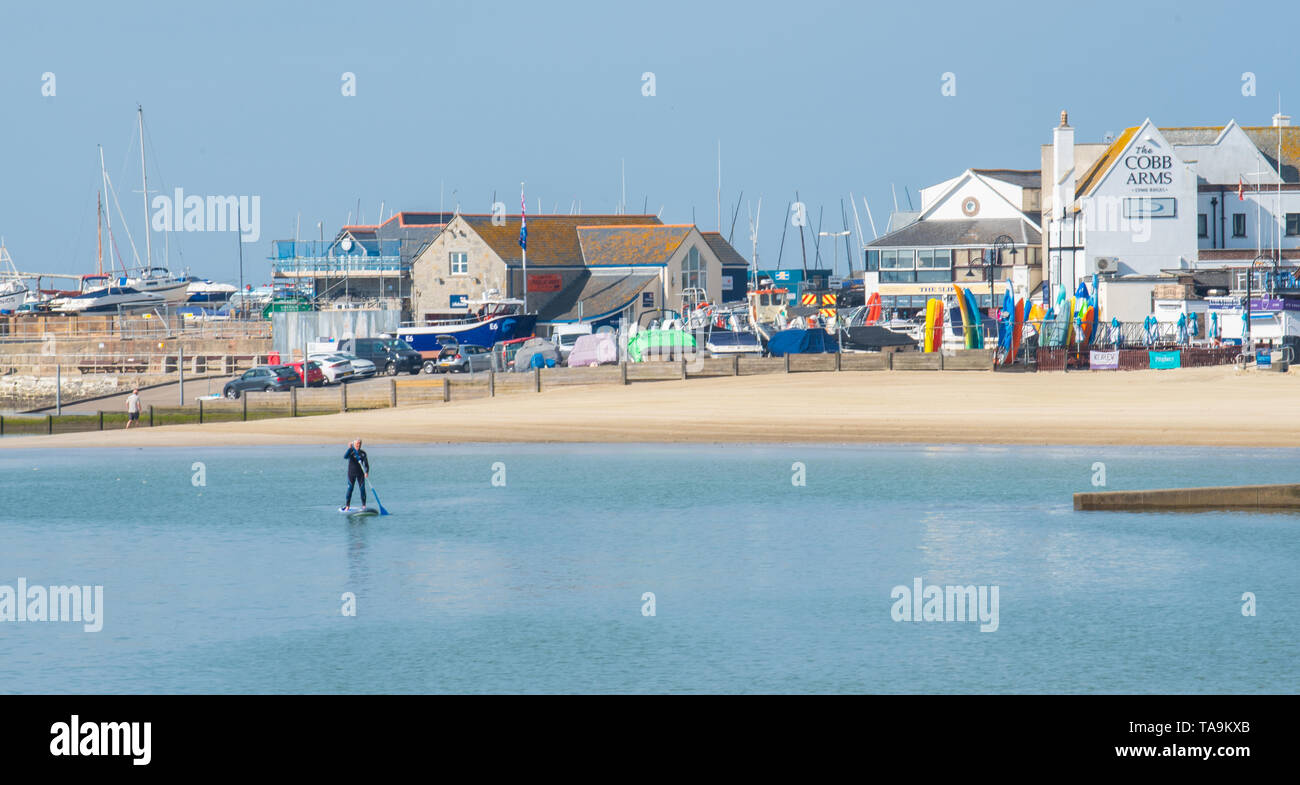Lyme Regis, dans le Dorset, UK. 23 mai 2019. Météo France : un glorieux matin à la pittoresque plage de la ville balnéaire de Lyme Regis. La station balnéaire populaire est calme et tranquille aujourd'hui en vue de la prochaine maison de banque mai. Une famille de paddle-boarder tire parti de la paix. On s'attend à ce que les foules affluent à la plage populaire de la semaine prochaine pour se prélasser dans le doux temps qui a été prévu dans toute la côte sud de l'Angleterre. Credit : Celia McMahon/Alamy Live News. Banque D'Images