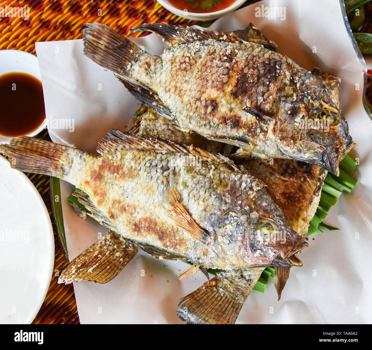 Le poisson tilapia grillé sur herbe avec le sel et la sauce chili sur la plaque en Asie Thai style poissons cuits brûler Banque D'Images