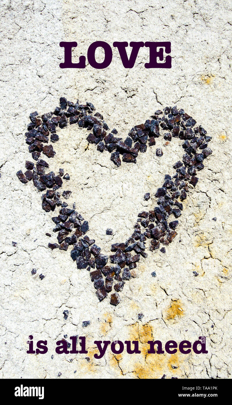 Une pierre rouge coeur de galets sur le sol sec du désert avec texte d'inspiration. Banque D'Images