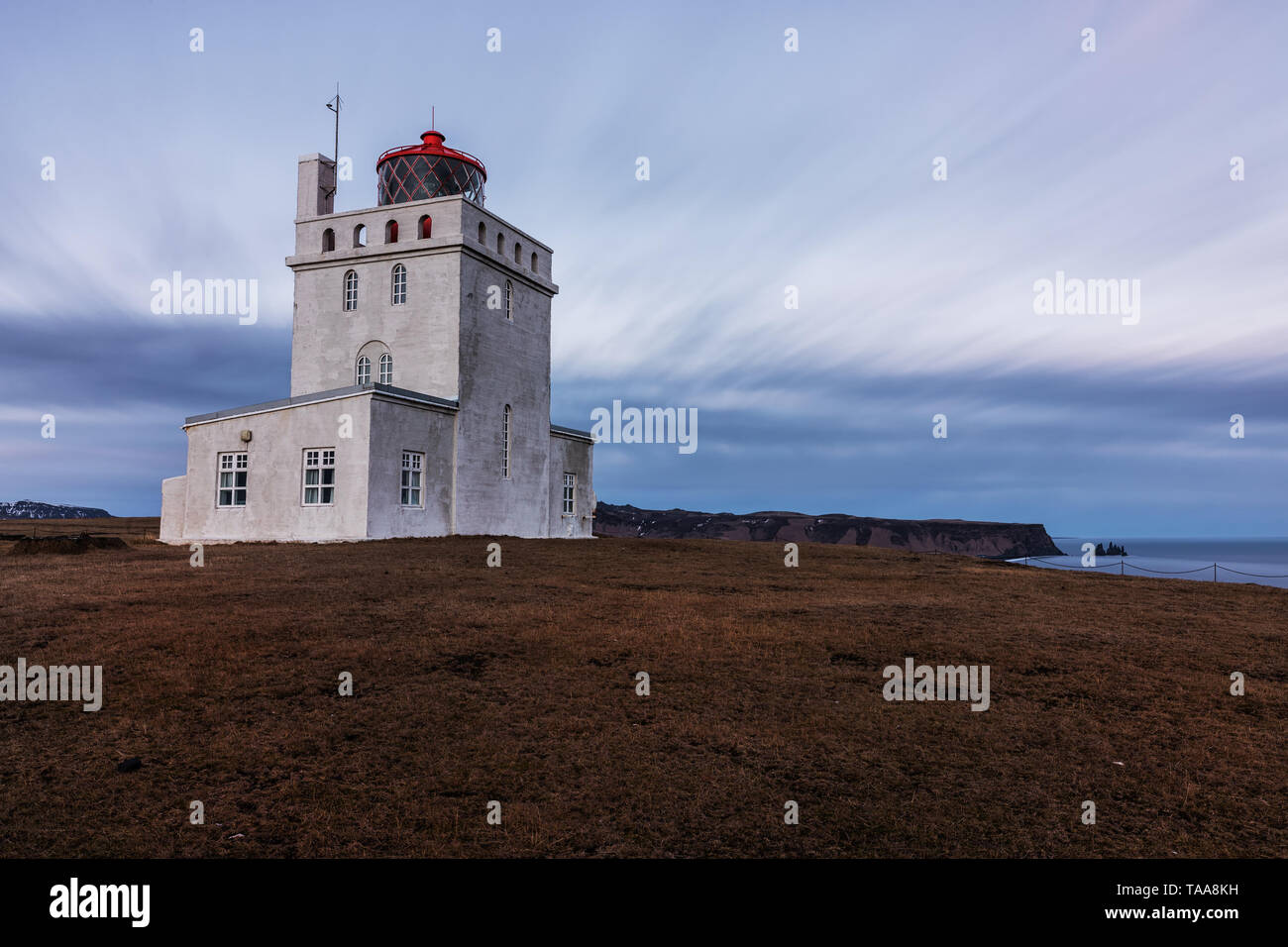 Phare Dyrholaey prises au coucher du soleil avec une longue exposition avec des nuages à Dyrholaey, Côte Sud, Islande Banque D'Images