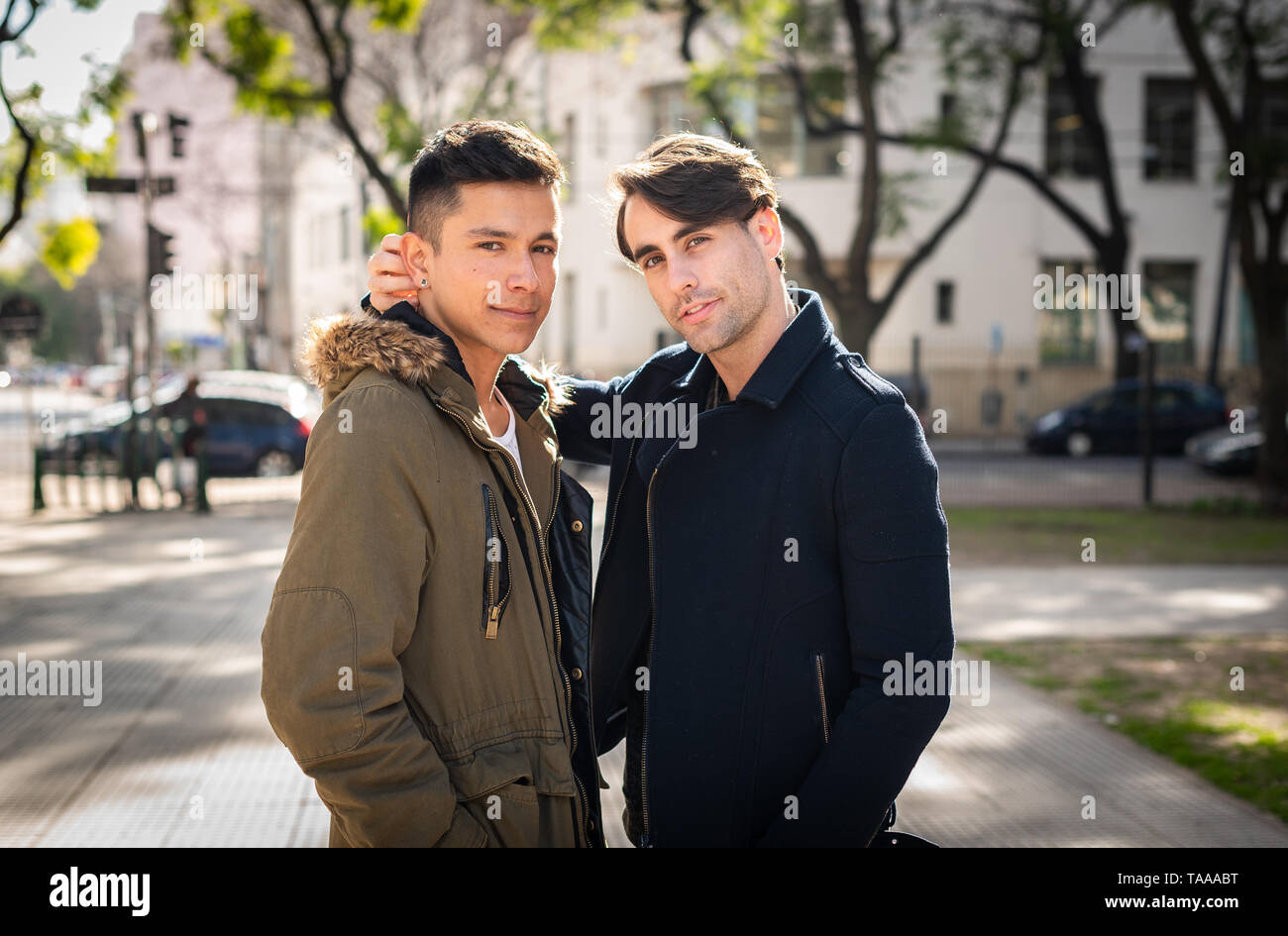 Les jeunes hommes adultes élégant gay couple looking at camera de sourire et d'être tendre au parc urbain à l'automne Banque D'Images