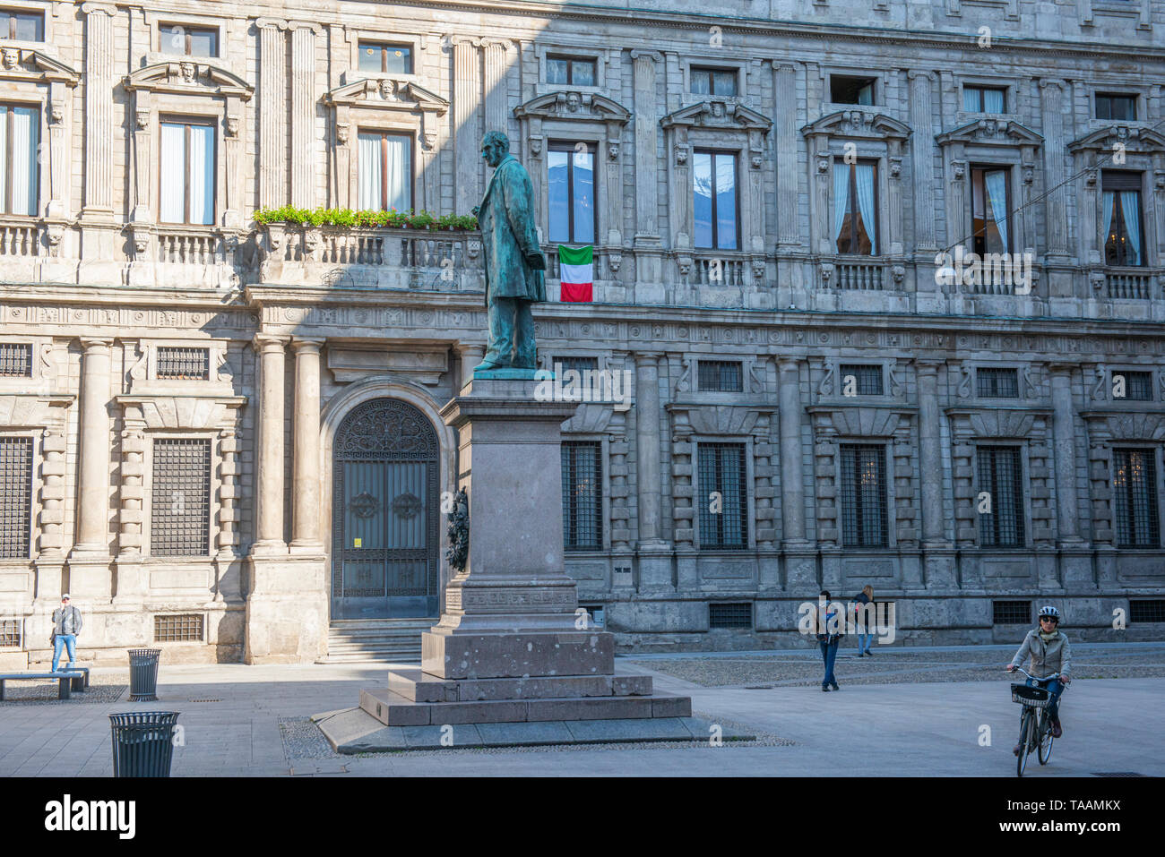 Milan, Italie - 23 mai 2019 : Les gens sont wolking le matin au square de San Fedele, statue de l'écrivain Alessandro Manzoni avec le drapeau italien i Banque D'Images