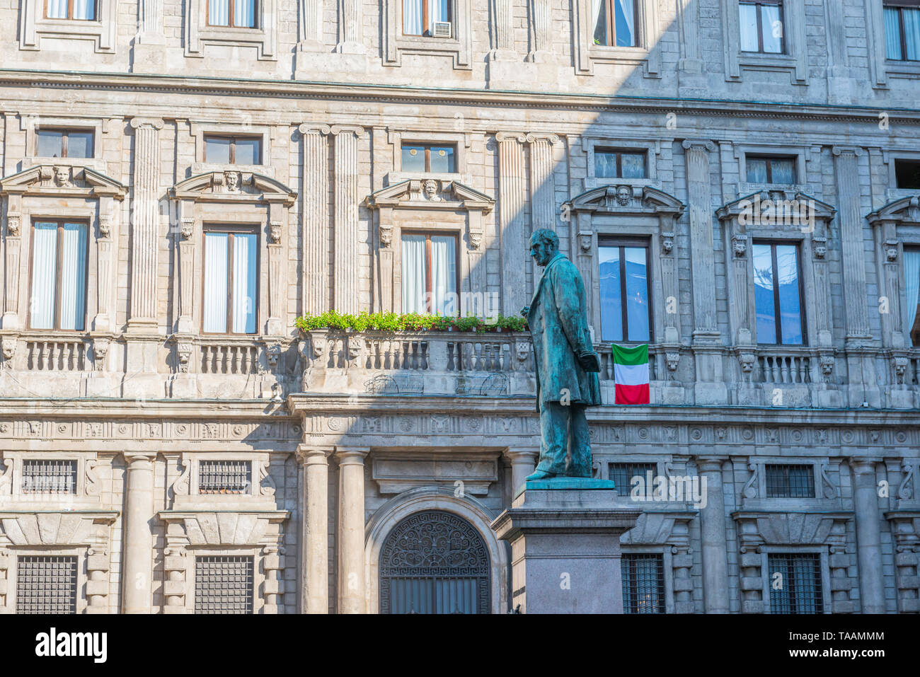 Milan, Italie - 23 mai 2019 : Les gens sont wolking le matin au square de San Fedele, statue de l'écrivain Alessandro Manzoni avec le drapeau italien i Banque D'Images