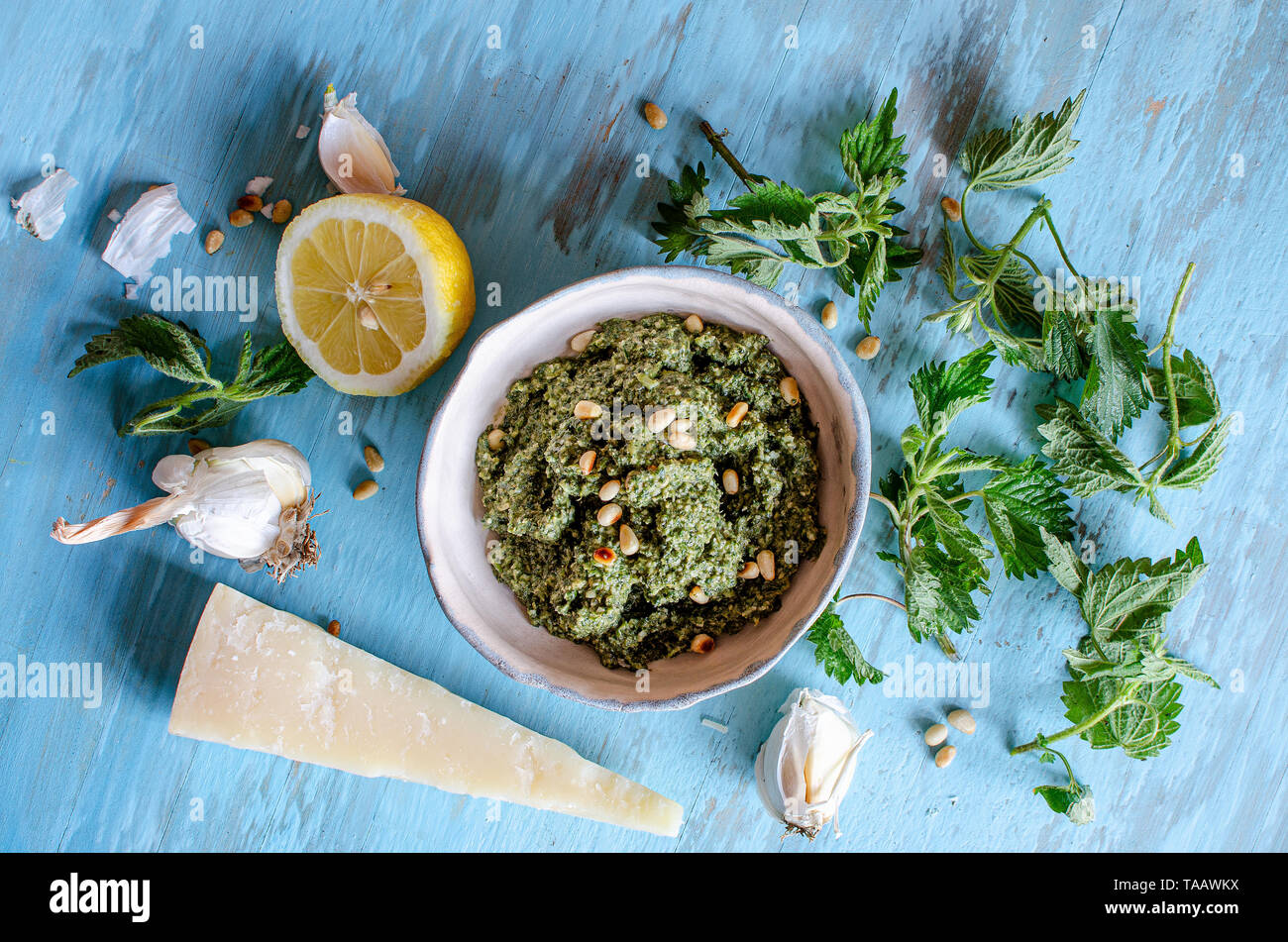 L'ortie pesto dans un plat sur une surface en bois bleu avec le parmesan, les noix de cèdre, de citron et d'ortie Banque D'Images