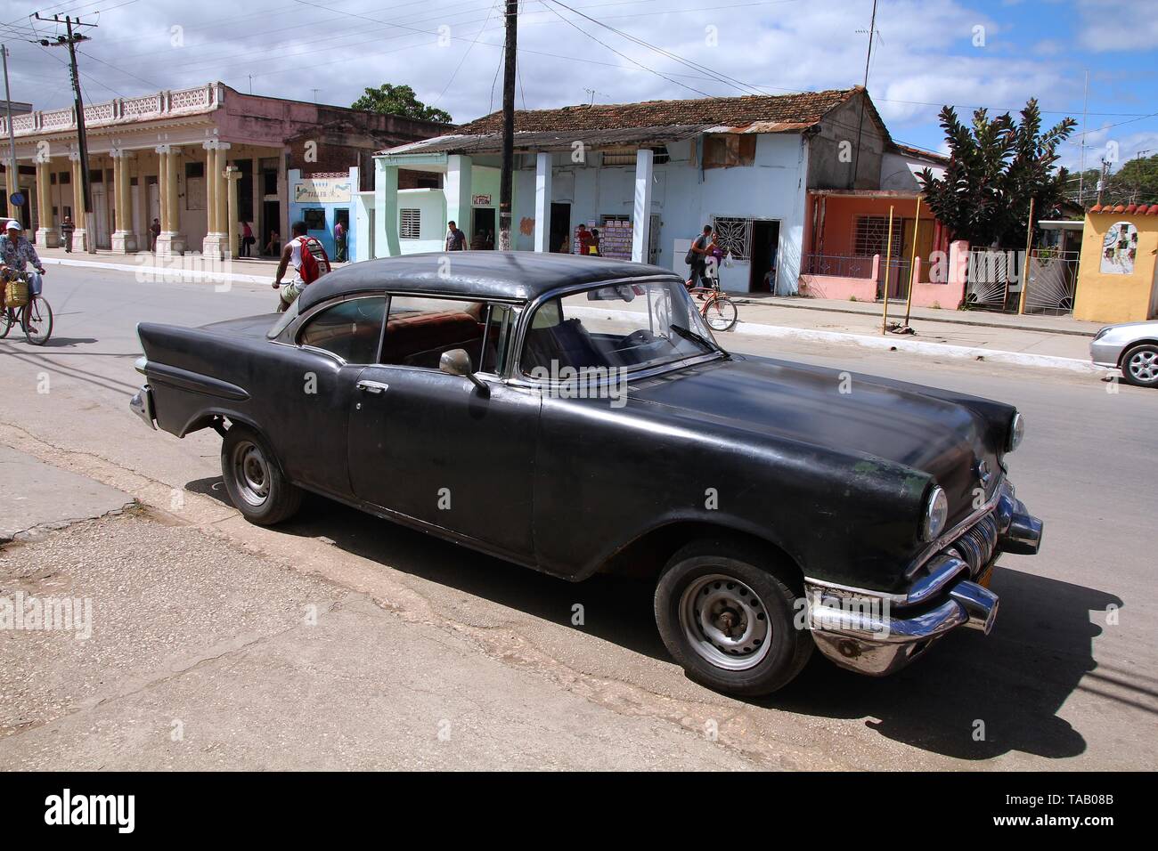 MORON, CUBA - février 19, 2011 : les gens à pied passé vieille voiture à Moron, Cuba. Cuba a l'un des taux de location par habitant élevés (38 pour 1000 personnes en 2008) Banque D'Images