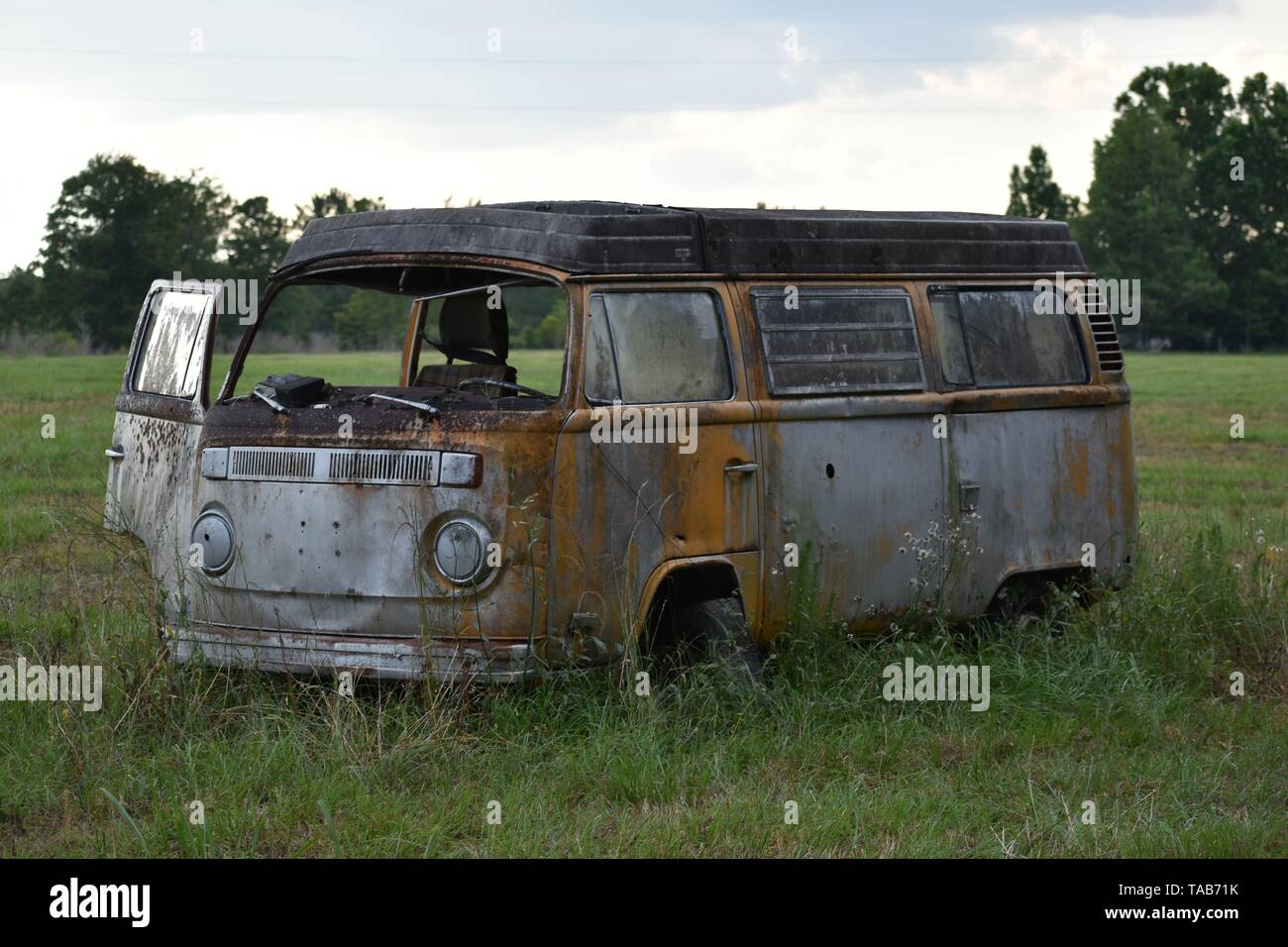 1976 Volkswagen Bus abandonnés assis dans un champ. Banque D'Images