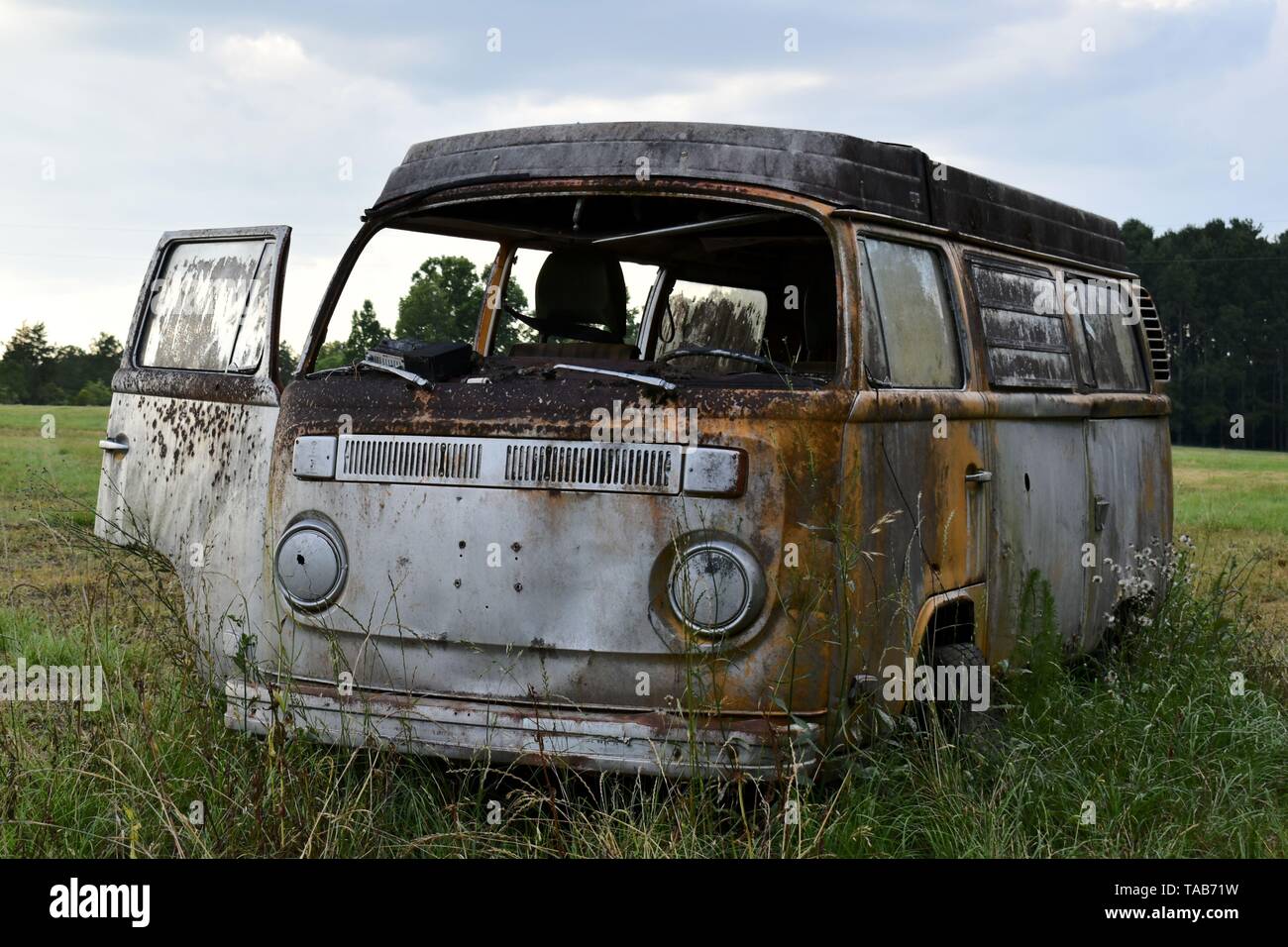 1976 Volkswagen Bus abandonnés assis dans un champ. Banque D'Images