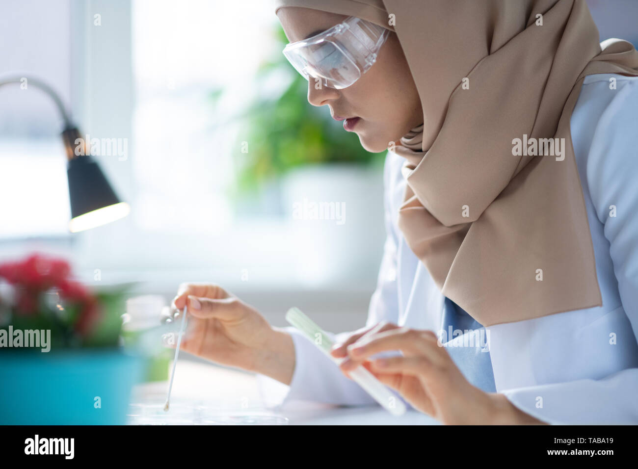 Lunettes de protection. Chimiste femelle portant des lunettes et une expérience de hijab Banque D'Images