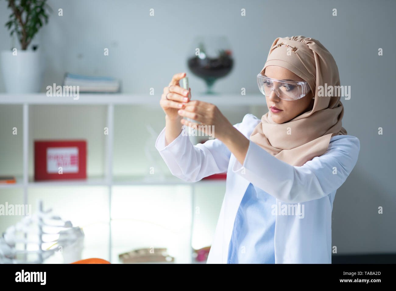 Chimiste à puce. Femme intelligente portant des lunettes et chimiste hijab holding test tube Banque D'Images