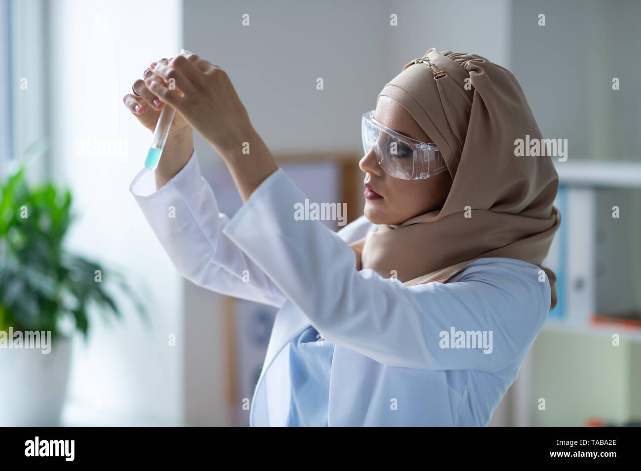 Tube de liquide. Chimiste femelle portant des lunettes à la recherche de tube à essai avec un liquide transparent Banque D'Images