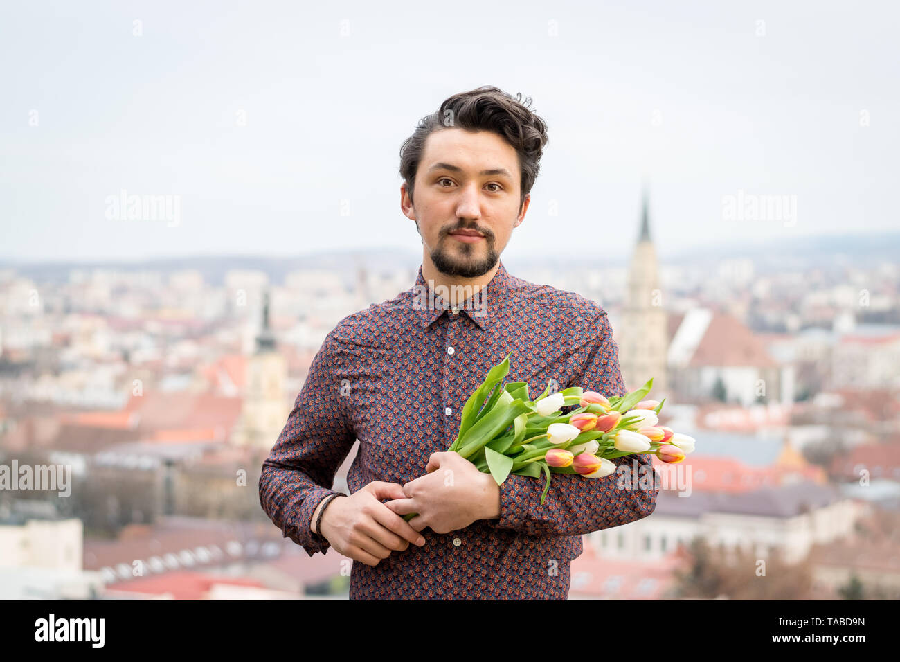 Portrait d'un beau jeune homme avec des fleurs de tulipe. Concept d'un homme tenant des fleurs tulipes comme cadeau pour une occasion spéciale . Banque D'Images