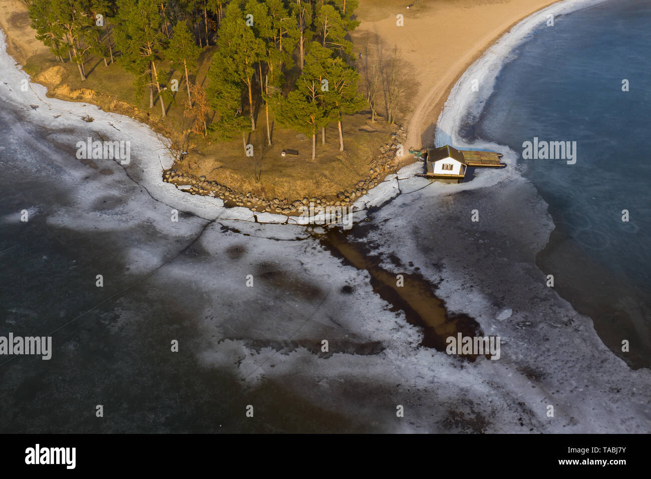 Vue aérienne de la rive du lac gelé et petit chalet en hiver sur la journée ensoleillée. Banque D'Images