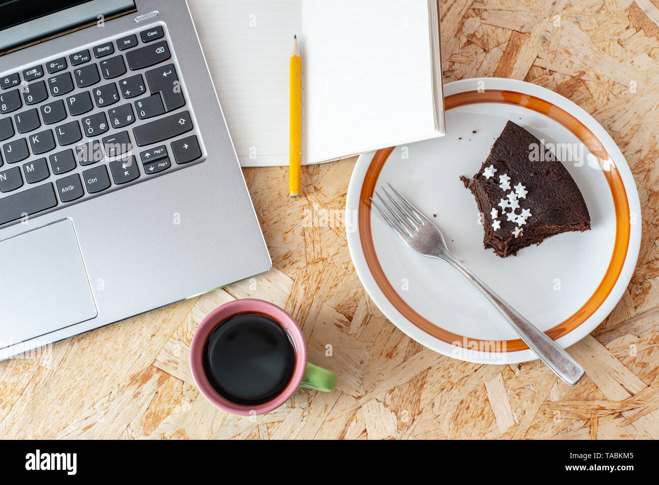 Un Ordinateur Portable Une Tasse De Cafe Une Plaque Avec Un Gateau Au Chocolat Un Ordinateur Portable Avec Un Crayon Sur Un Bureau En Bois A L Etat Brut Vue Du Dessus Photo
