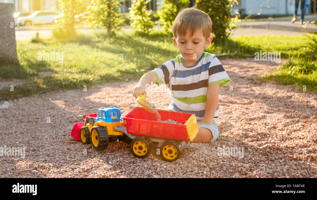 Portrait Of Cute 3 Ans Bebe Garcon Assis Sur L Aire De Jeux Au Parc Et Jouer Avec Des Jouets En Plastique Chariot Enfant S Amuser Et Jouer Photo Stock Alamy