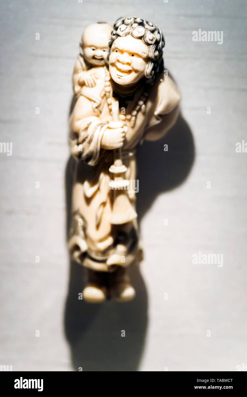 Figure aïnou portant un enfant et d'un instrument de musique par Kokeisai Samsho figurine Netsuke en ivoire, 1900-1930 Banque D'Images