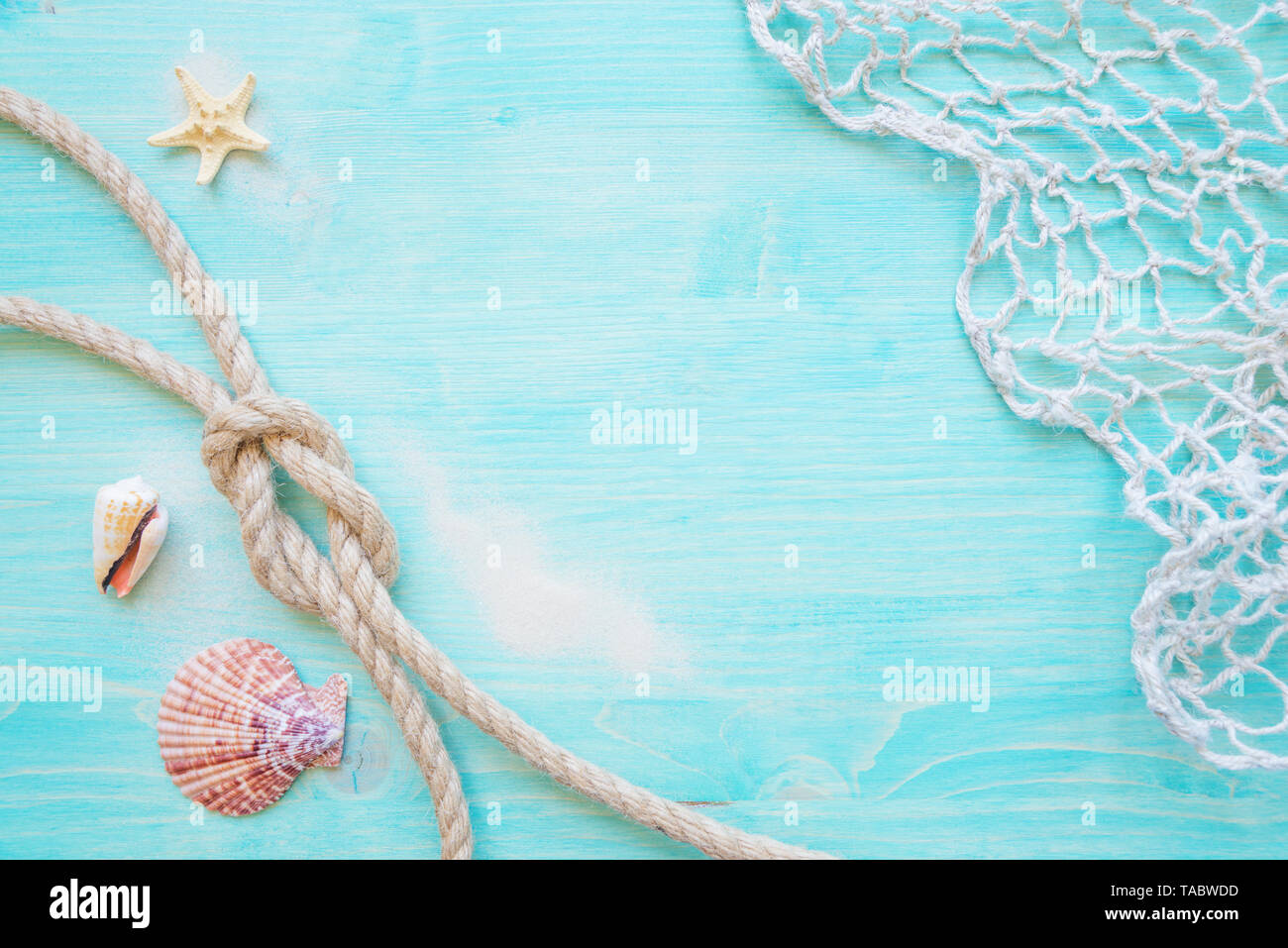 Corde de chanvre brut knot, la mer, des étoiles de hells et la pêche réseau sont sur le fond bleu pâle terrasse en bois. Concept Marine Banque D'Images