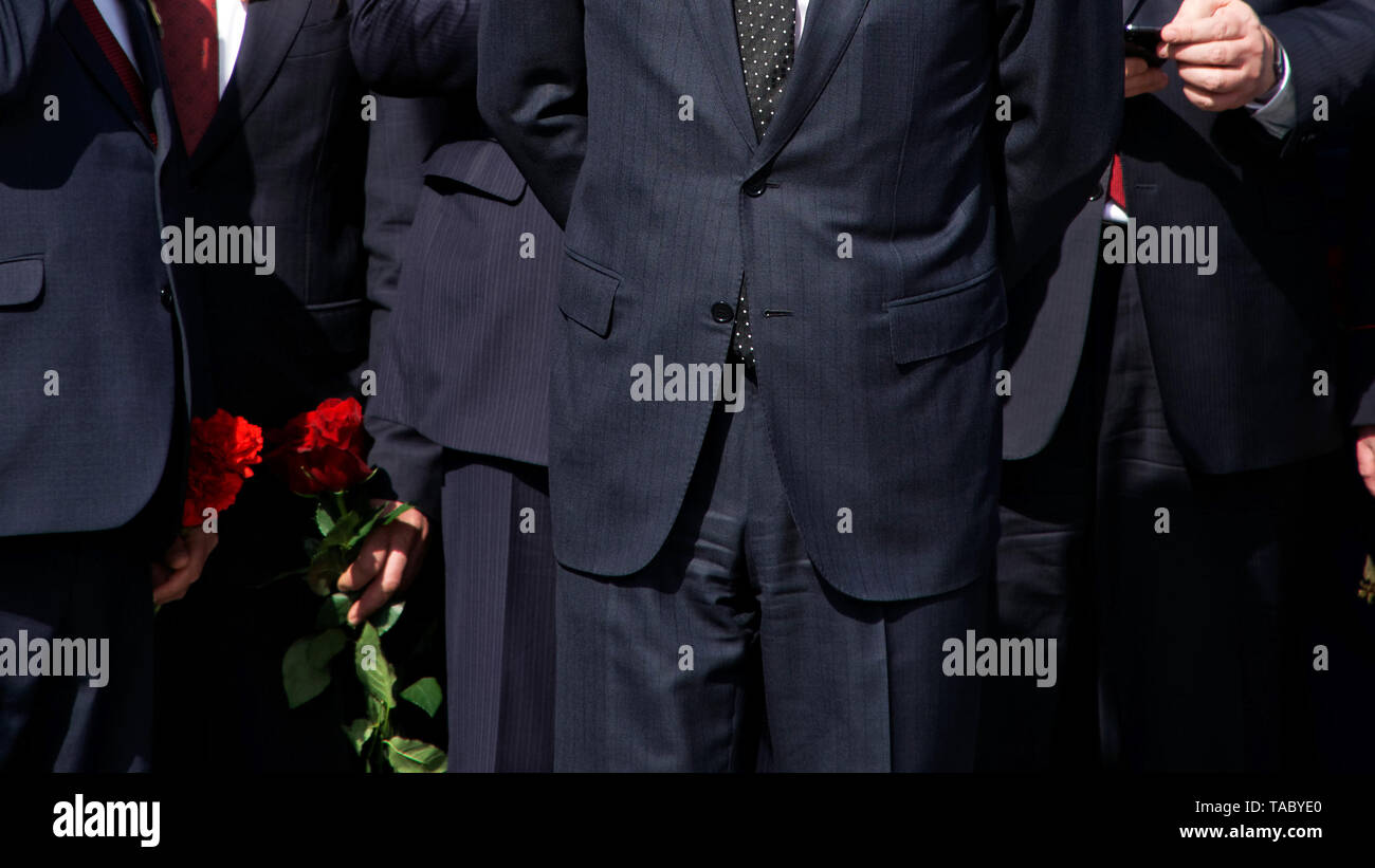 Les hommes en costumes noirs strict avec les fleurs rouges. La direction de l'entreprise. La délégation officielle. Sans visage. Banque D'Images