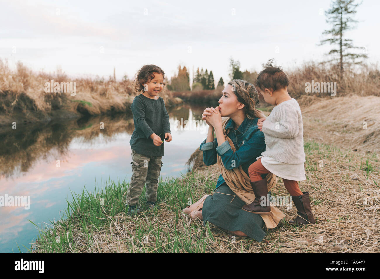 Maother et des enfants jouant avec un brin d'herbe à une rivière Banque D'Images