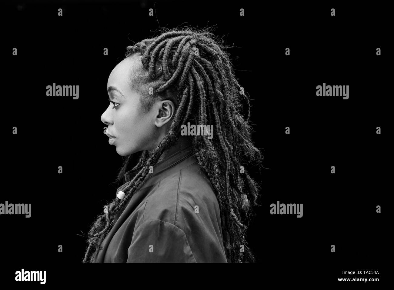 Femme de profil avec des dreadlocks en face de fond noir Banque D'Images