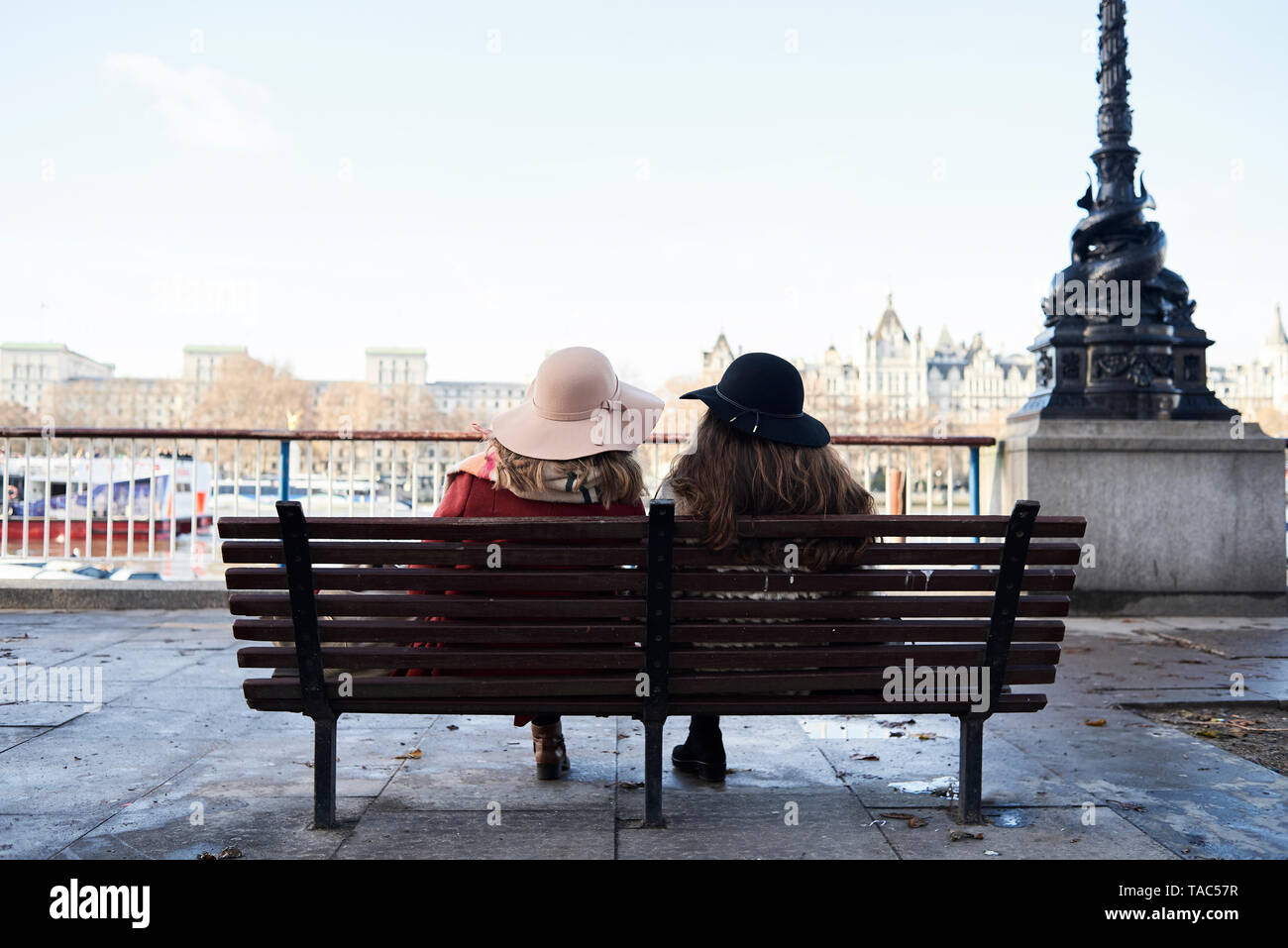 UK, Londres, vue arrière de deux femmes assises sur un banc à Tamise, promenade Banque D'Images