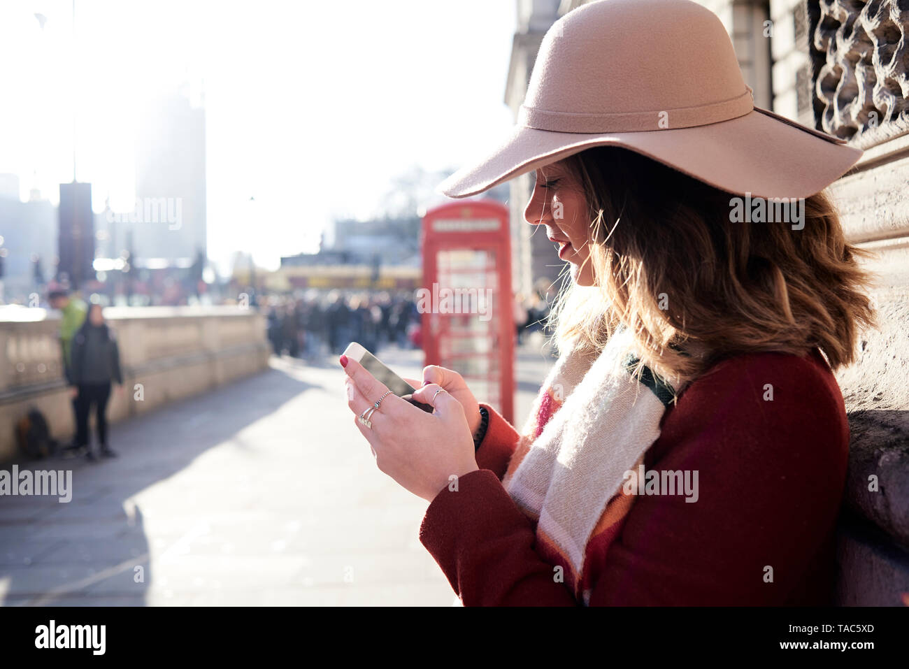 UK, Londres, femme dans la ville portant un floppy hat using cell phone Banque D'Images