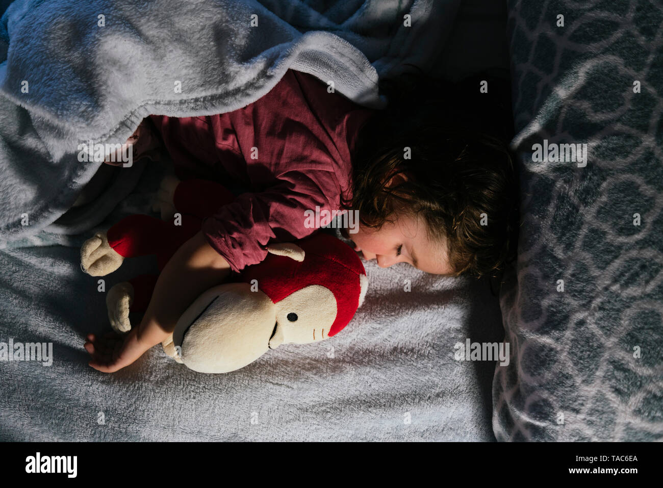 Bébé fille dormir dans le lit avec un chien en peluche orang-outan Banque D'Images