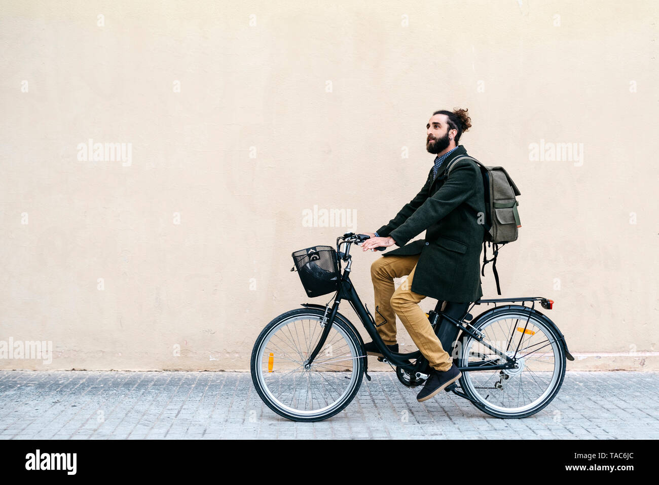 Man riding e-bike le long d'un mur Banque D'Images