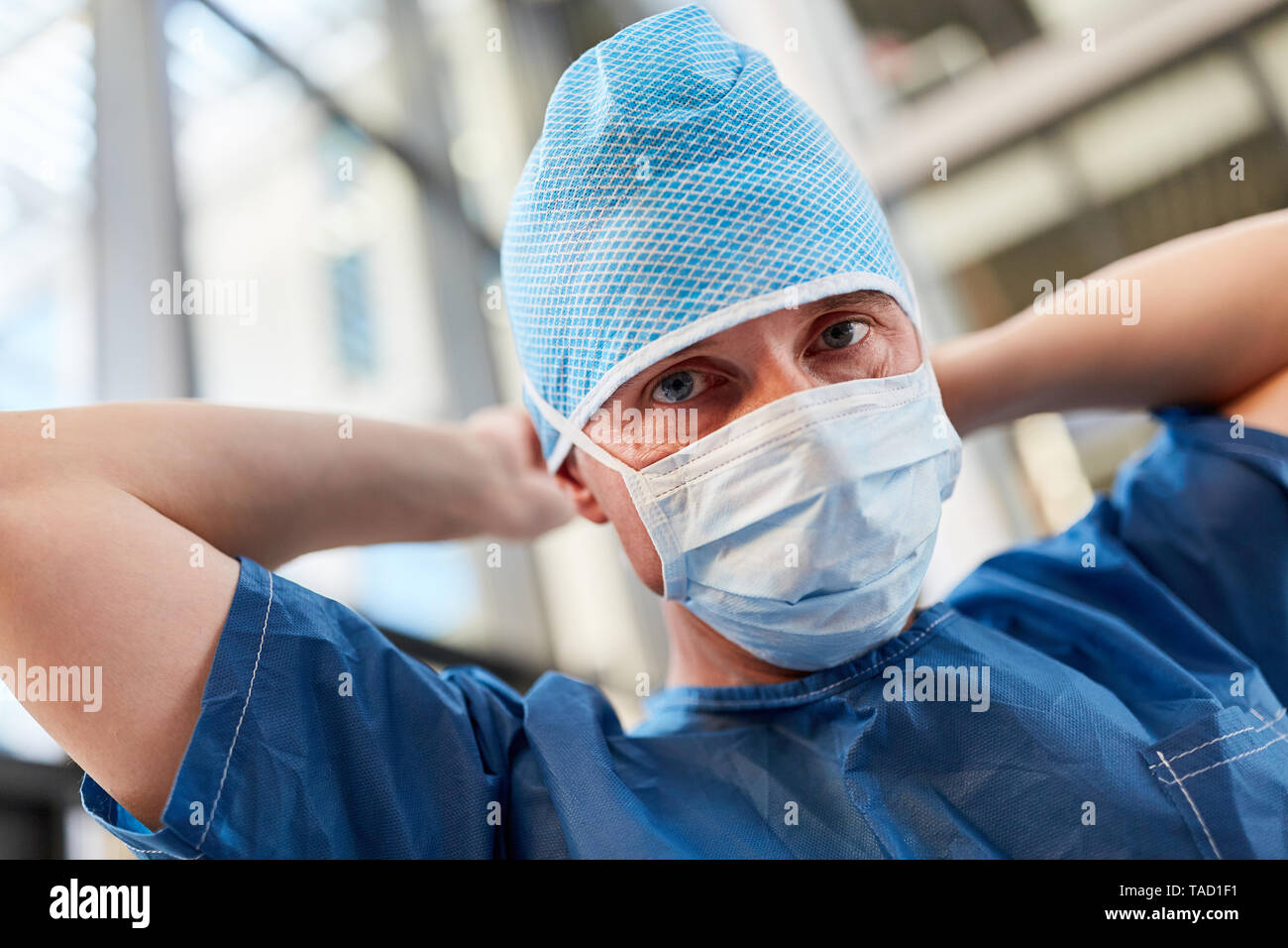 Médecin comme chirurgien dans la salle d'urgence en bleu avec les vêtements chirurgicaux masque chirurgical et capot Banque D'Images