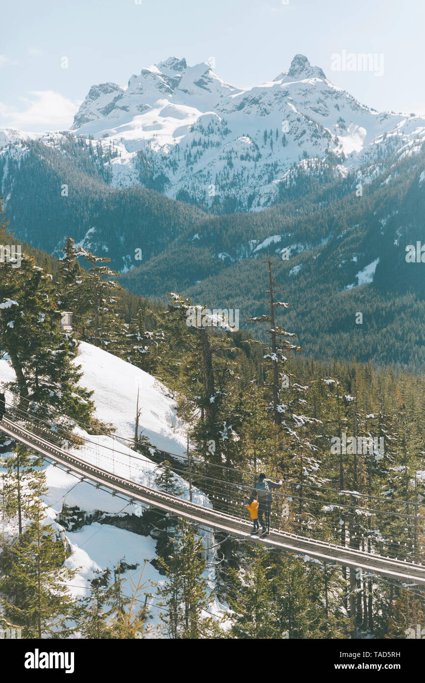Père et fils marchant sur un pont suspendu dans les montagnes, Squamish, Canada Banque D'Images