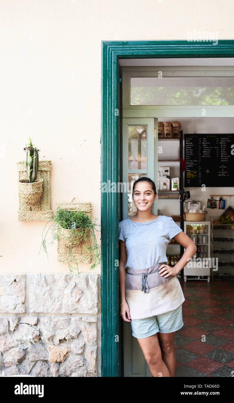 Portrait of smiling woman standing at porte d'entrée d'un café Banque D'Images