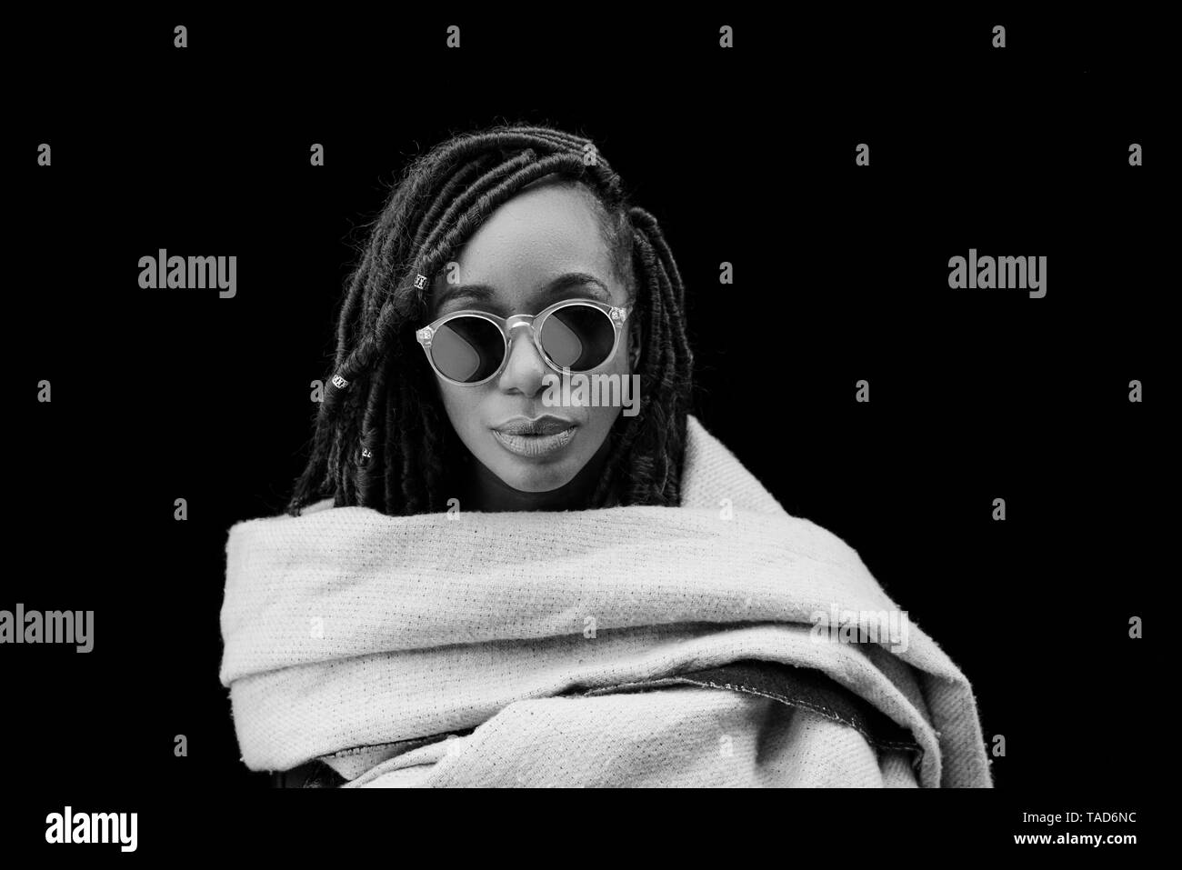 Portrait de femme avec des dreadlocks enveloppées dans une couverture en face de fond noir Banque D'Images Portrait de femme avec des dreadlocks enveloppées dans une couverture en face de fond noir Banque D'Images