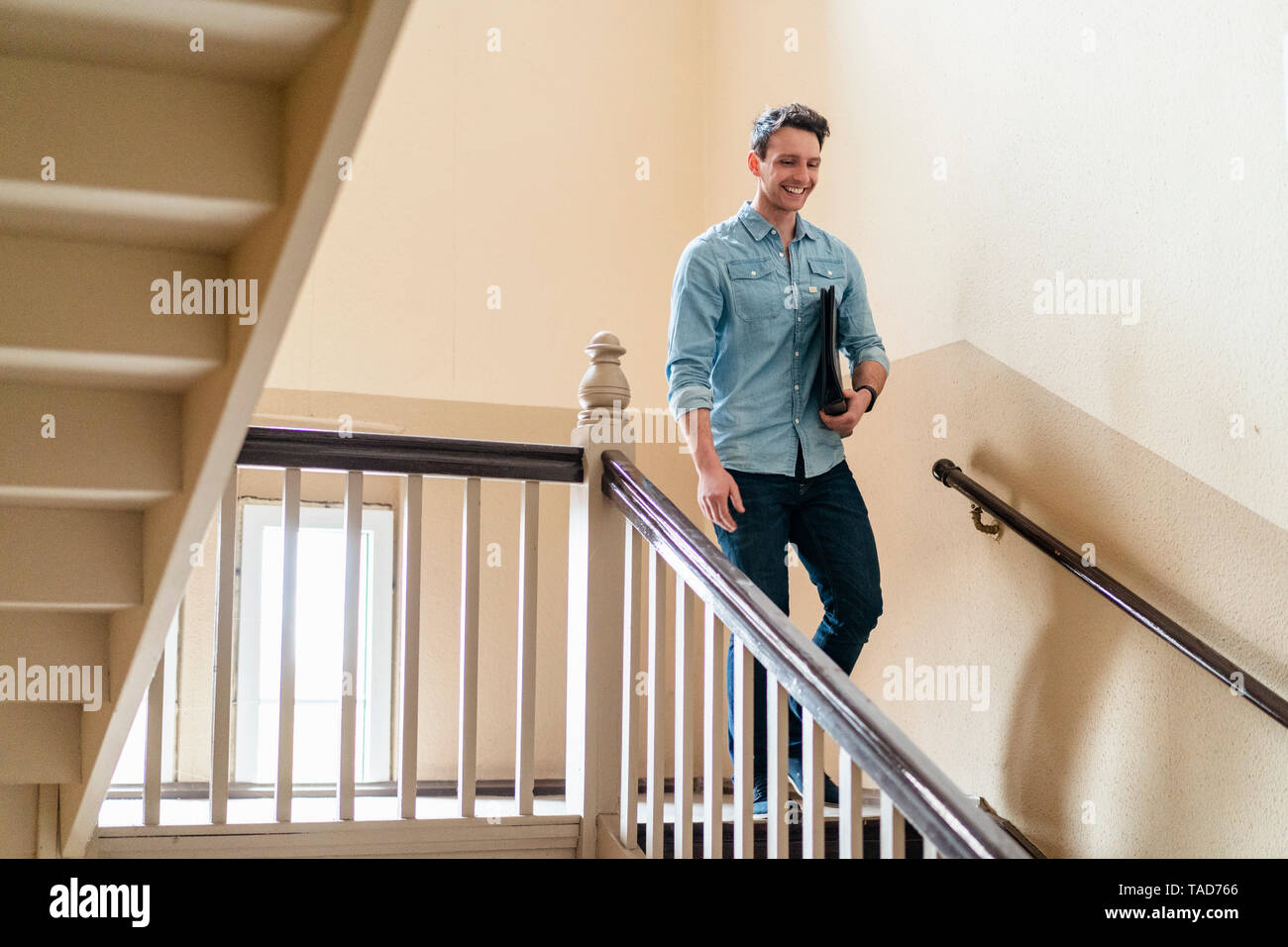 Smiling man walking down d'escalier Banque D'Images