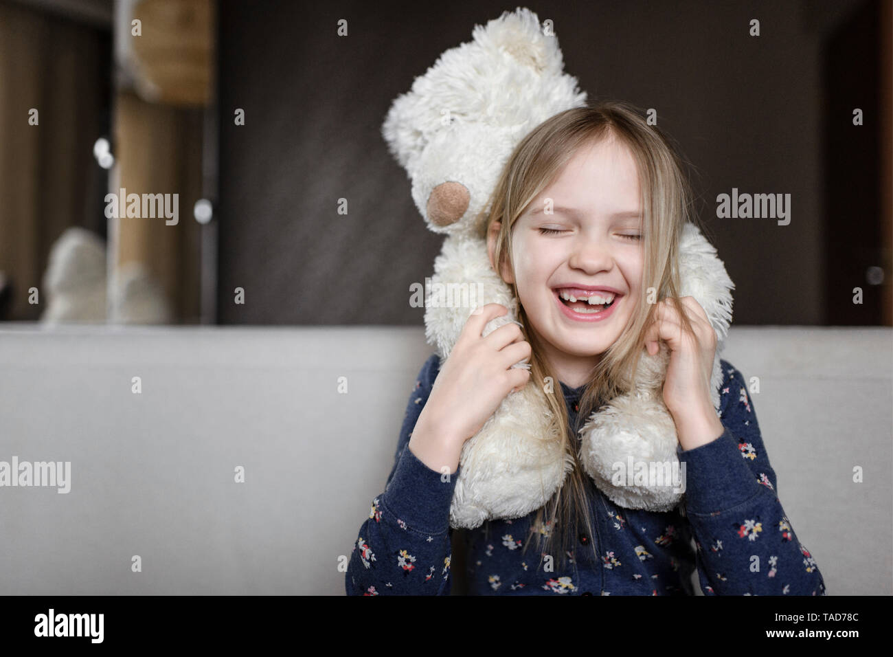 Portrait of laughing little Girl with tooth gap holding white teddy bear Banque D'Images