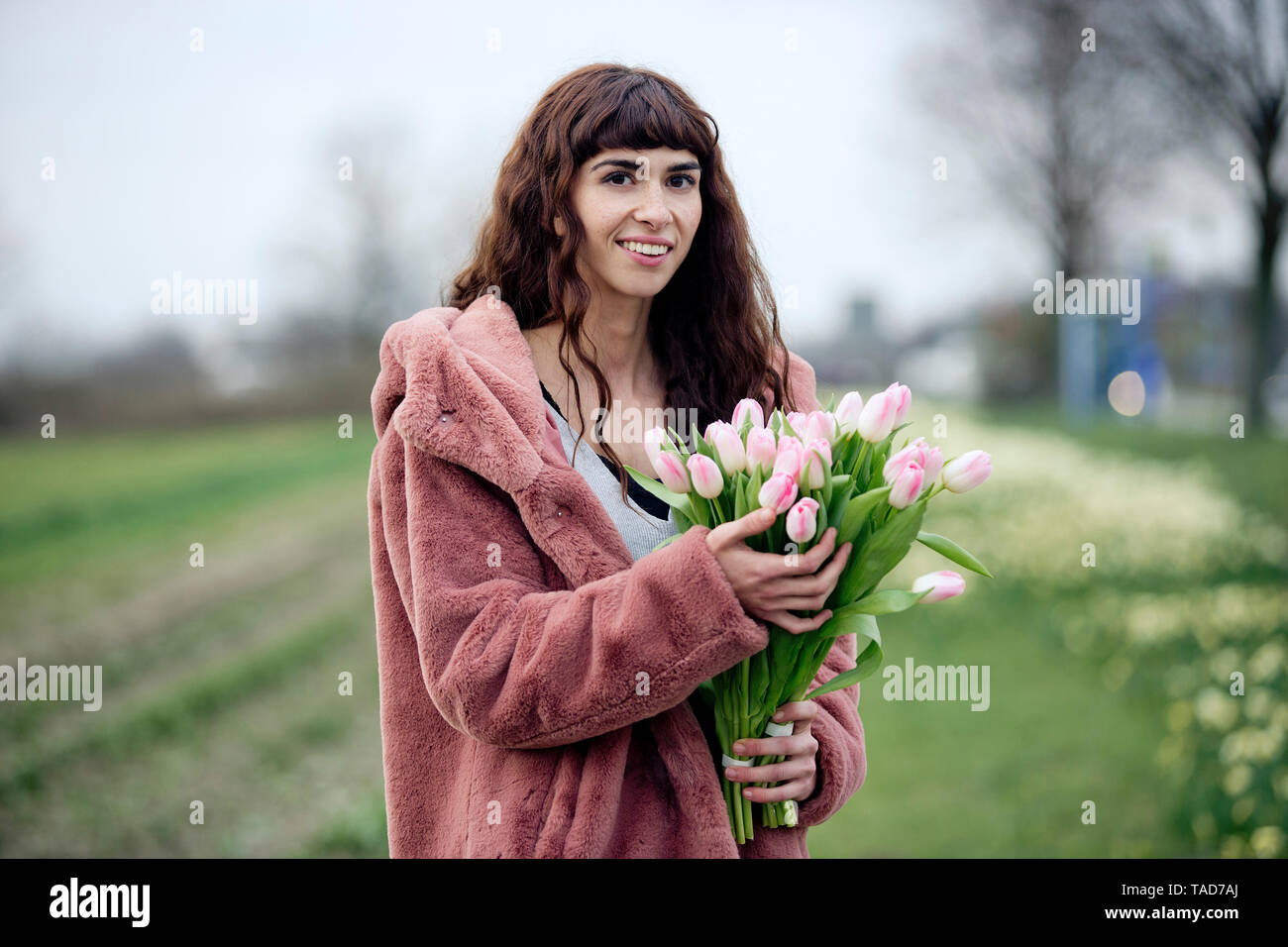 Jeune femme avec bouquet de tulipes et manteau rose Banque D'Images