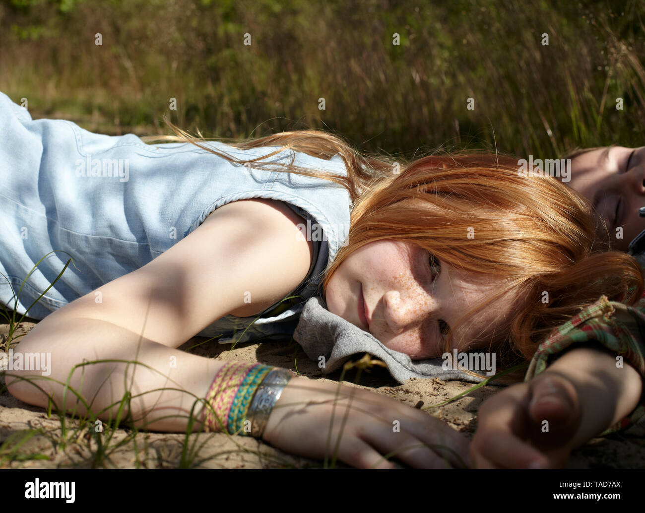 Portrait de jeune fille rousse allongé sur un sol sableux Banque D'Images