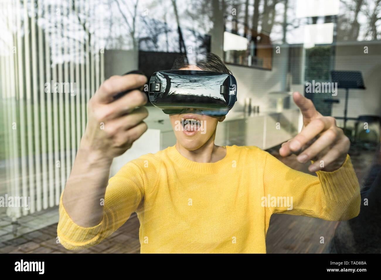 Portrait de femme étonné derrière la vitre à l'aide de lunettes de réalité virtuelle Banque D'Images
