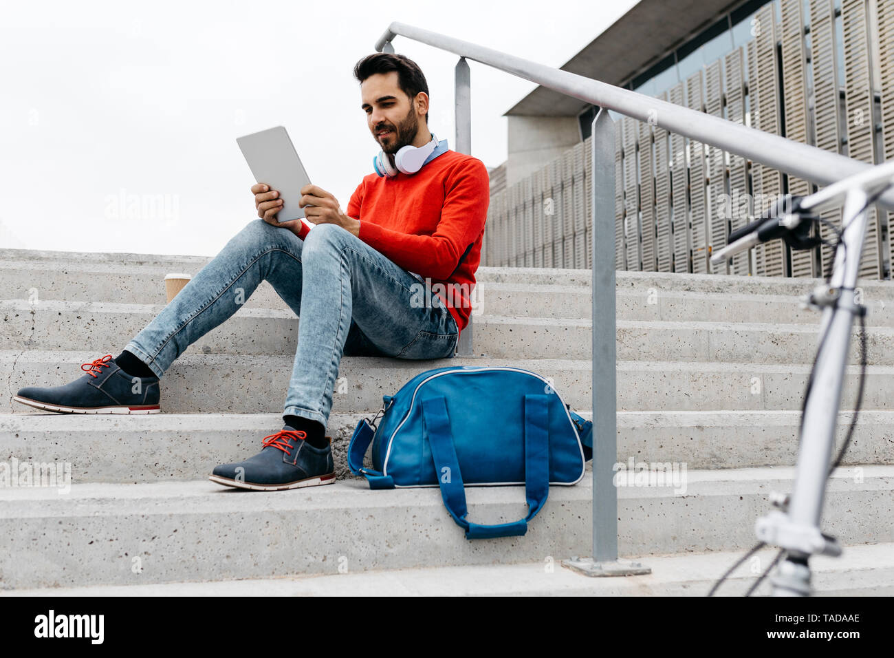 Businessman sitting escaliers dans la ville, à l'aide de son laptop et écouteurs Banque D'Images