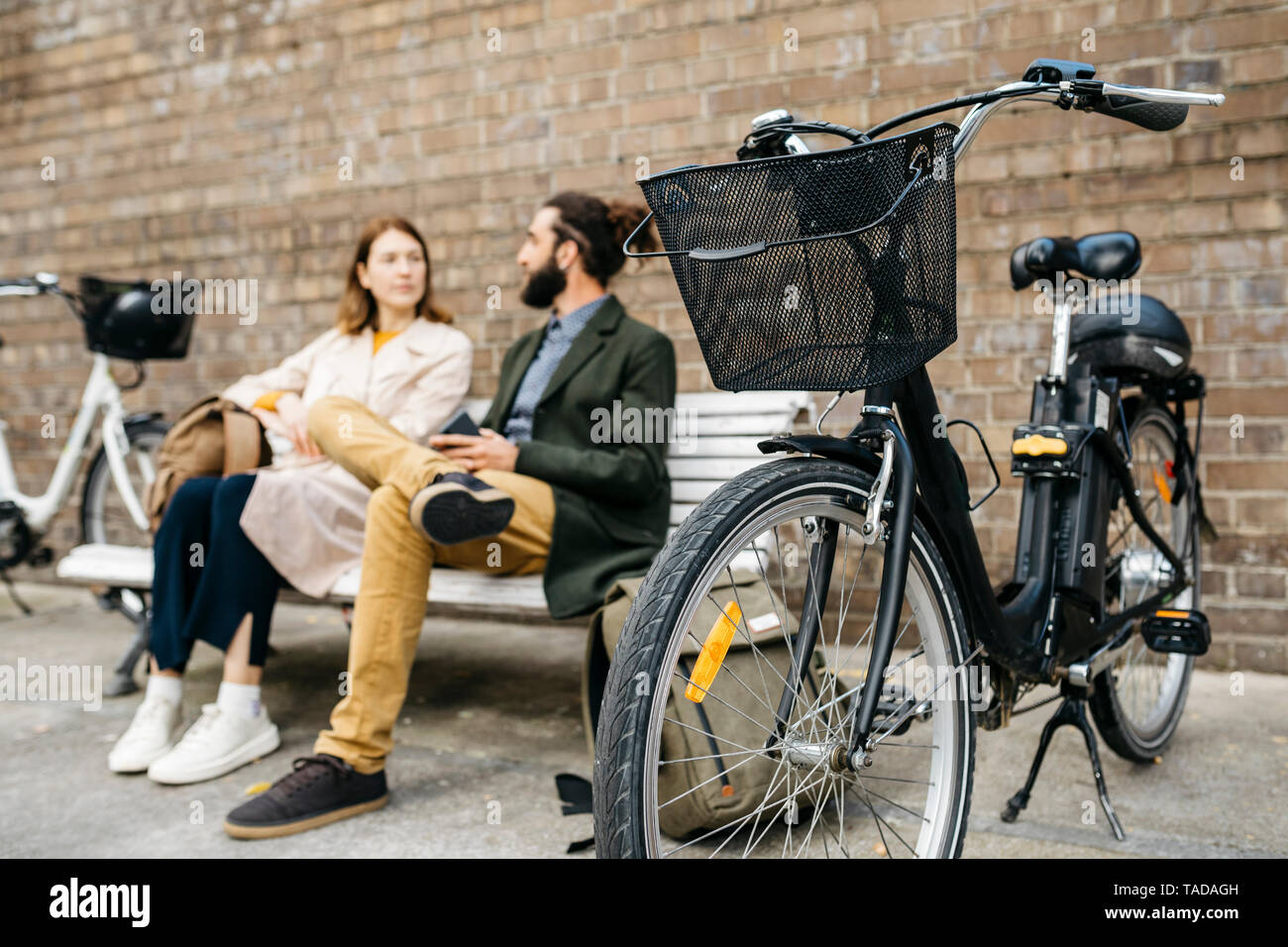 Couple assis sur un banc à côté d'e-bikes talking Banque D'Images