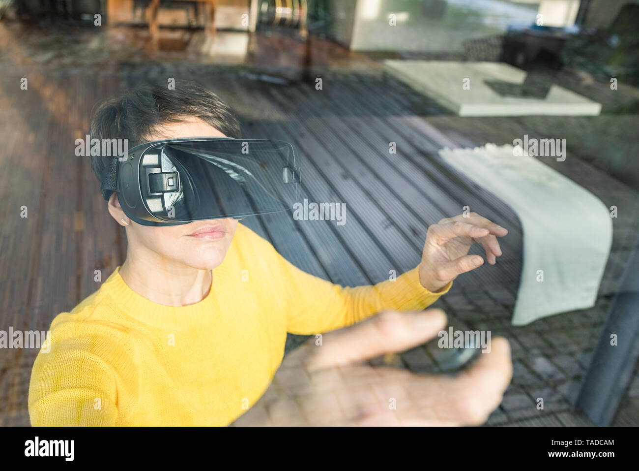 Portrait de femme derrière la vitre à l'aide de lunettes de réalité virtuelle à la maison Banque D'Images
