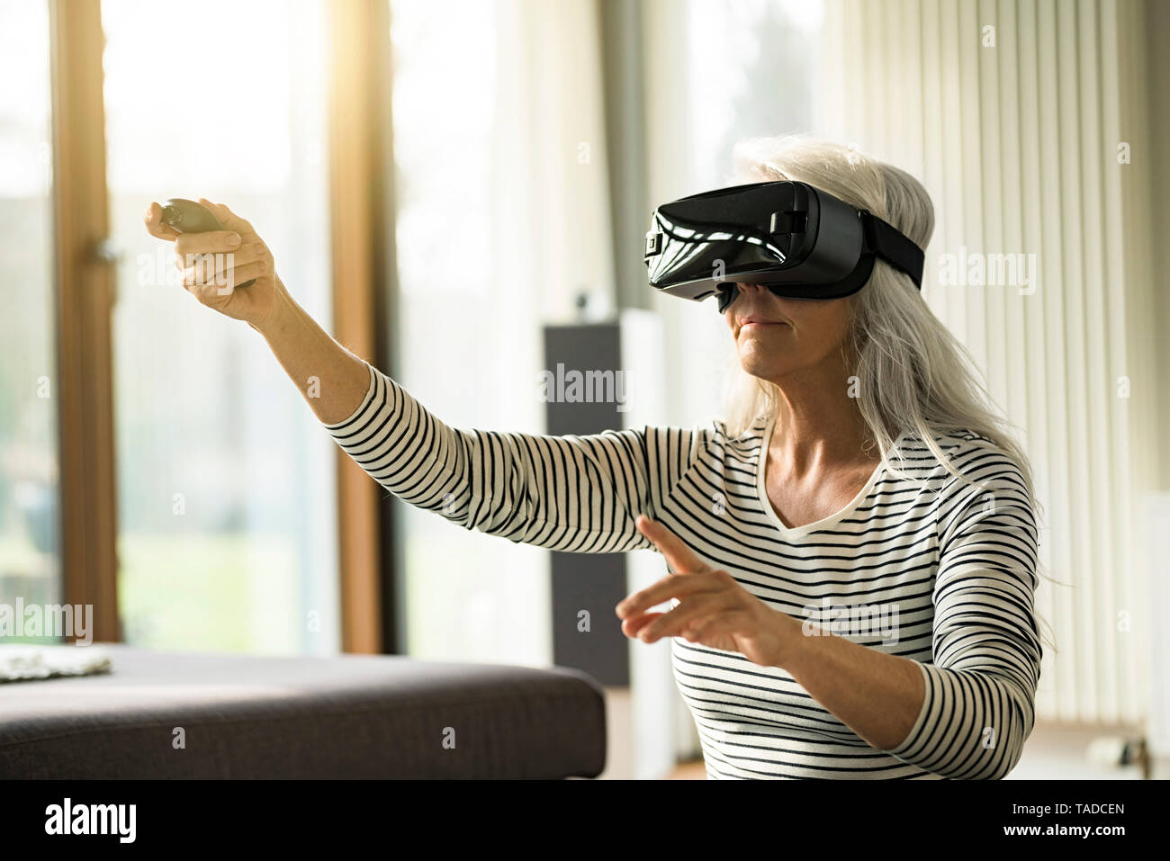 MAture woman using Virtual Reality Lunettes à la maison Banque D'Images