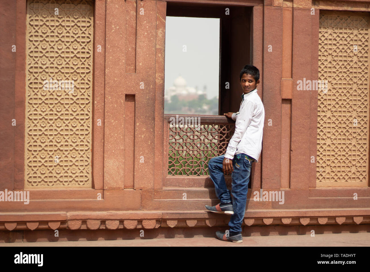 Jeune Indien garçon au fort rouge avec le Taj Mahal montrant en arrière-plan. Banque D'Images
