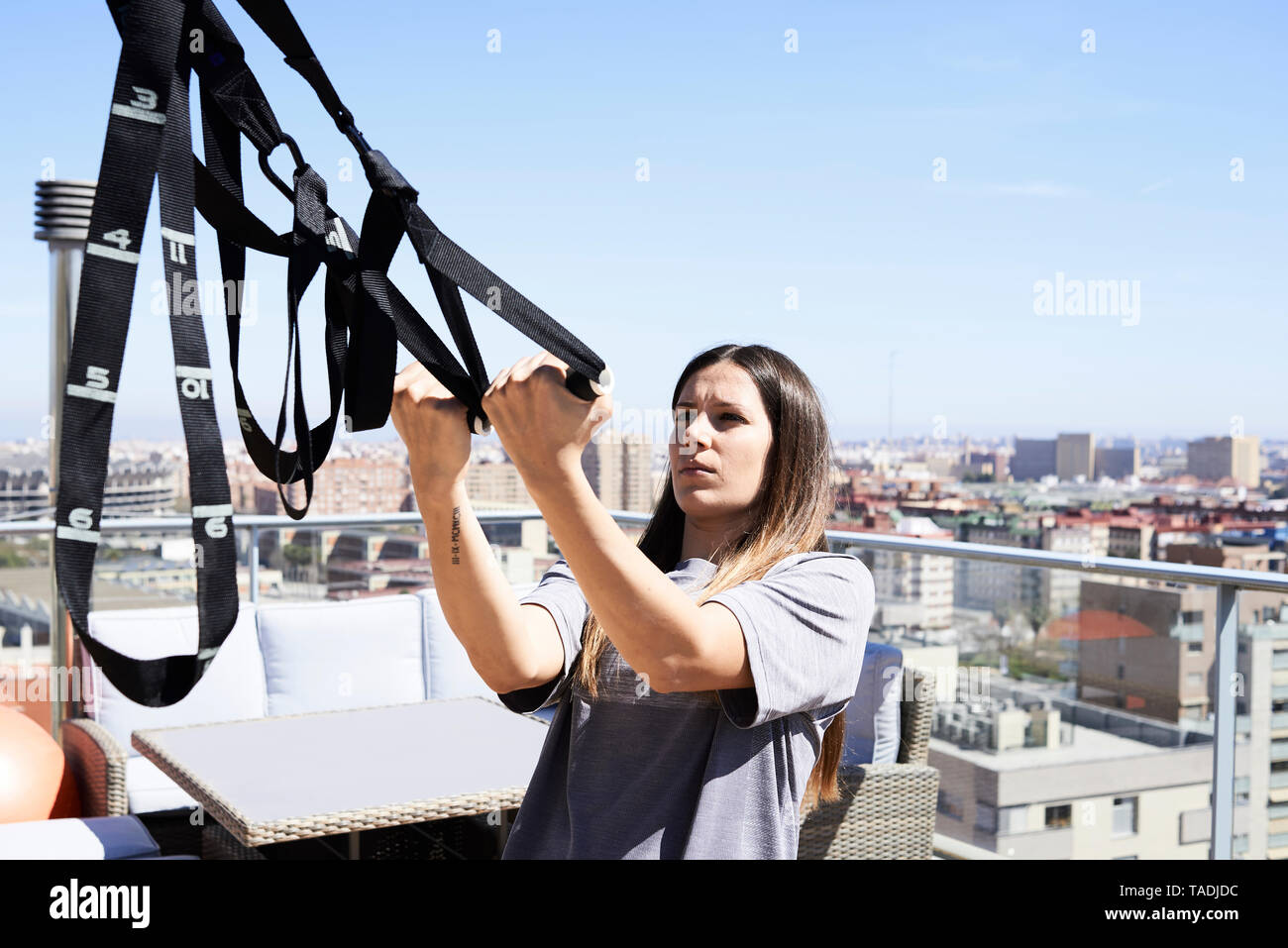 Jeune femme sportive faisant la formation de suspension sur la terrasse du toit Banque D'Images