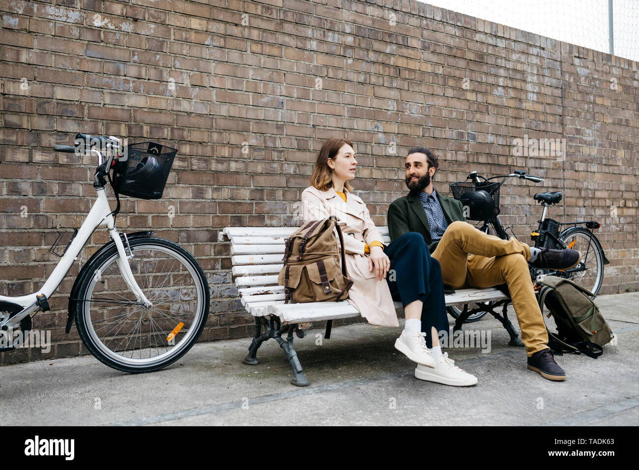 Couple assis sur un banc à côté d'e-bikes talking Banque D'Images