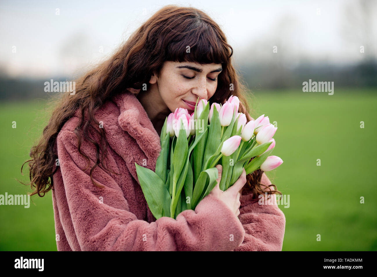 Jeune femme avec bouquet de tulipes et manteau rose Banque D'Images