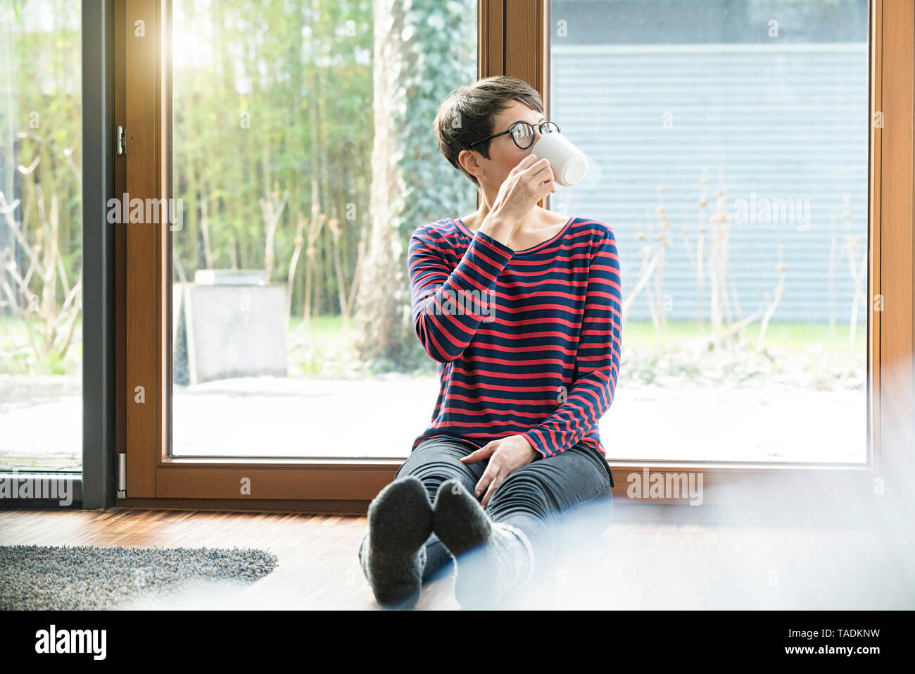 Femme assise sur le sol en face de la porte de terrasse de café potable Banque D'Images