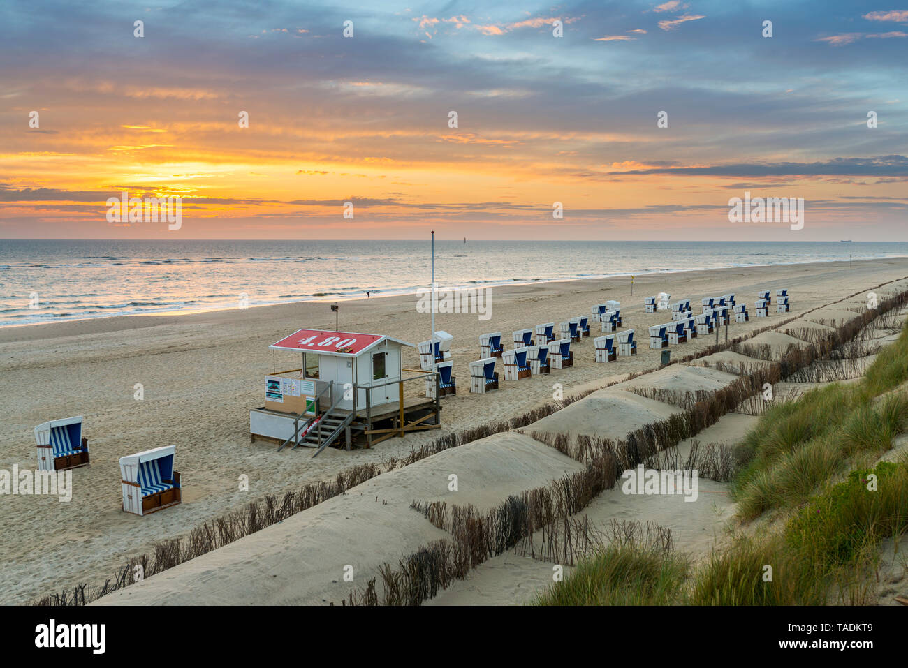 Allemagne, Sylt, Mer du Nord, plage de sable avec chaises de plage à capuchon dans le coucher du soleil Banque D'Images
