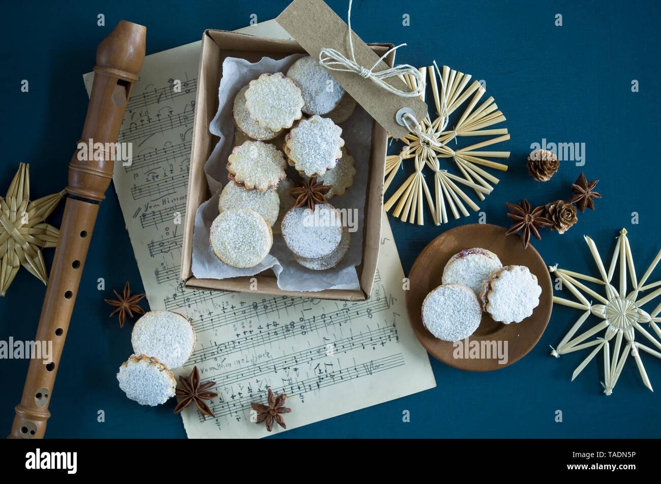 Cookies de Noël Spitzbuben dans une boîte, feuille de musique, enregistreur, étoiles de paille, l'anis étoilé, les cônes de mélèze, gift tag Banque D'Images