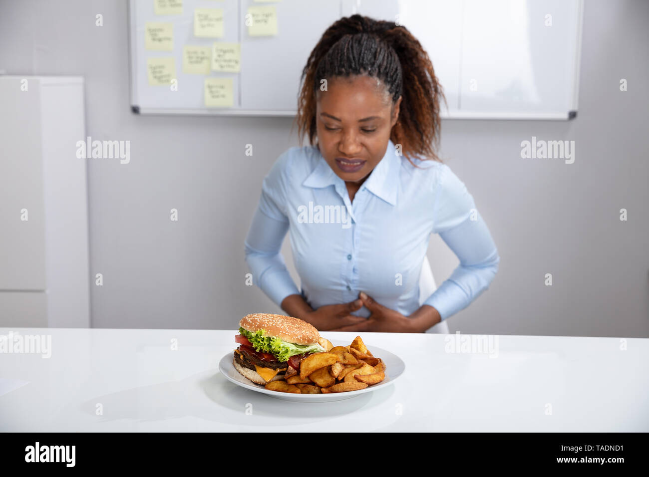 Jeune femme souffrant de douleurs à l'estomac pendant le petit-déjeuner Banque D'Images